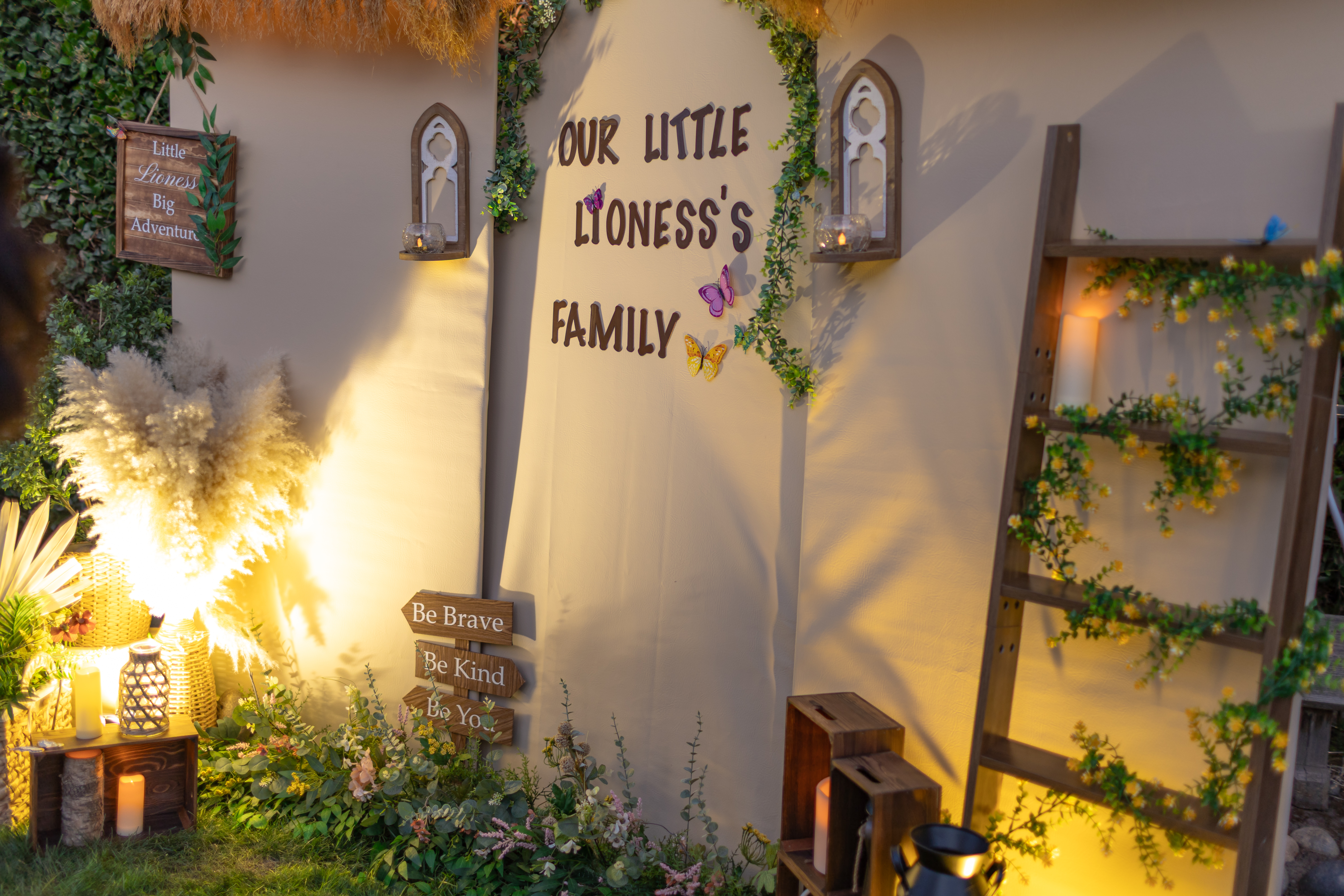 Illuminated event backdrop with custom lettering, cascading greenery, candles, and a ladder of flowers